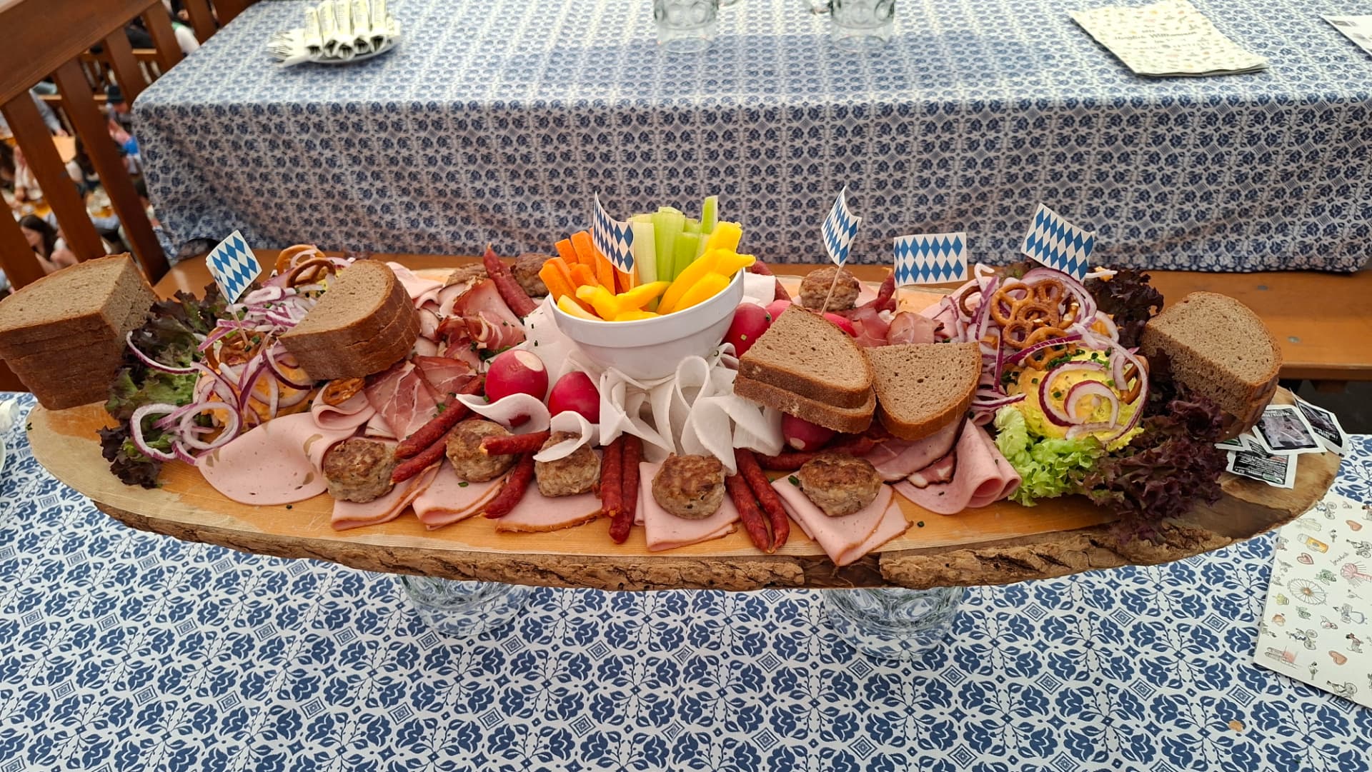 Large Bavarian Brotzeit platter with sausages, cold cuts, radishes, bread, pretzels and Bavarian flags at Oktoberfest in Munich.